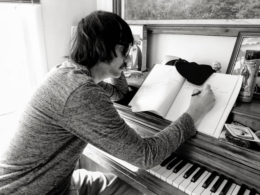 Hawk Foxman writing in a notebook at his piano